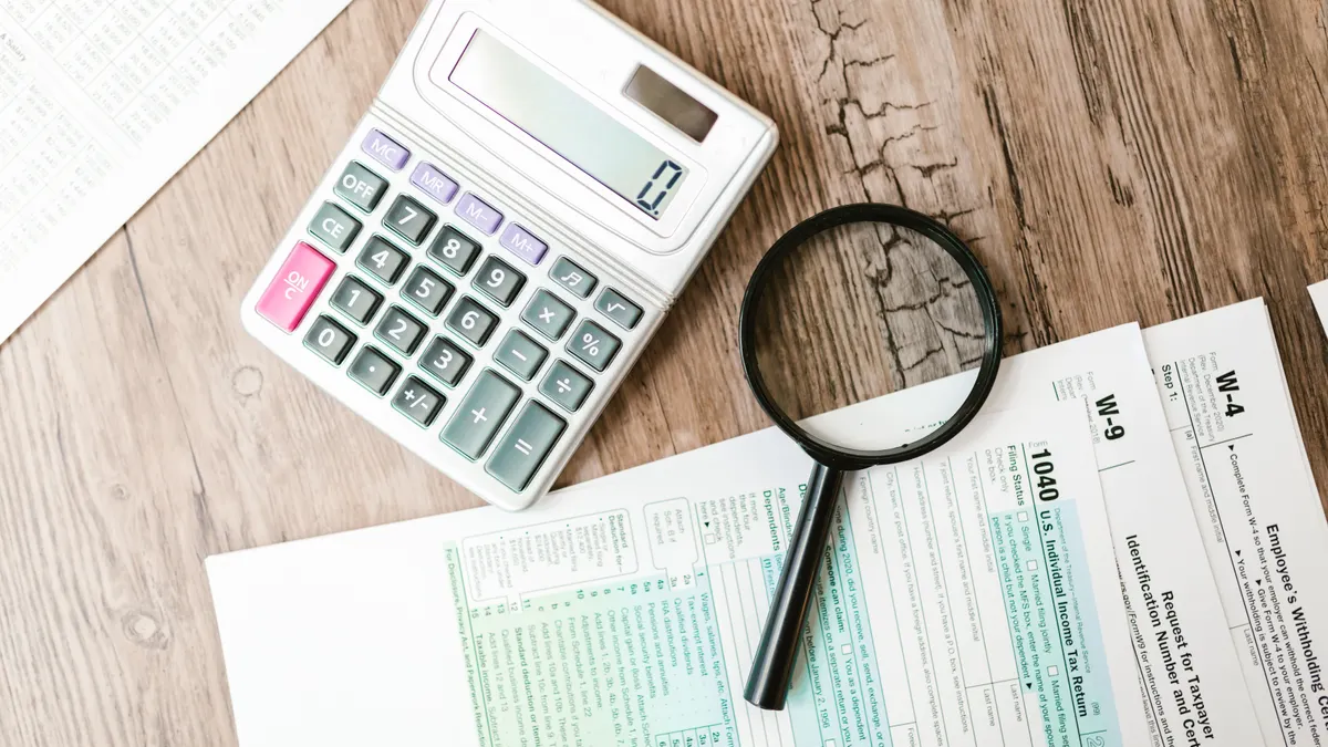 2026 federal income tax brackets explained Calculator and magnifying glass on tax forms