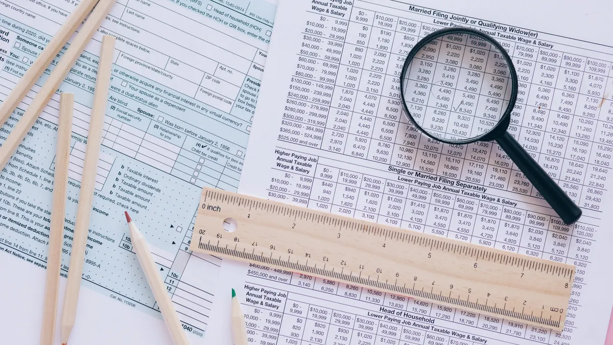 Earned Income Tax Credit: eligibility basics Tax forms under a magnifying glass with pencils