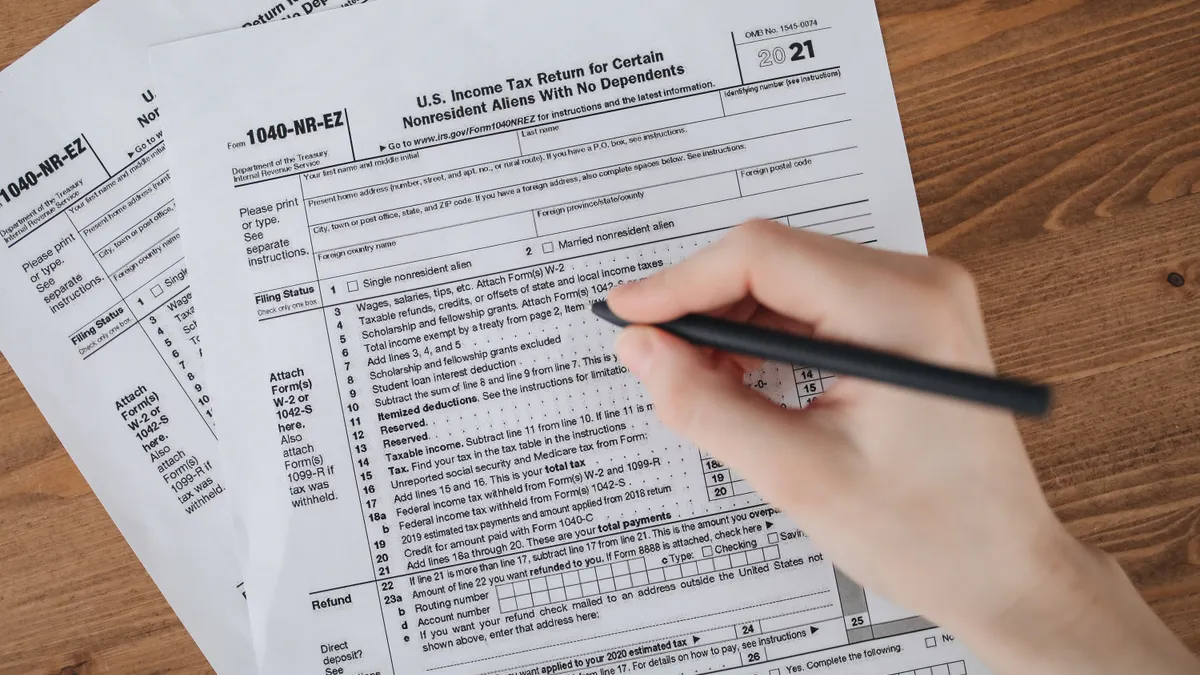 Estimated taxes for self-employed filers: who has to pay them Hand using pen on IRS tax forms